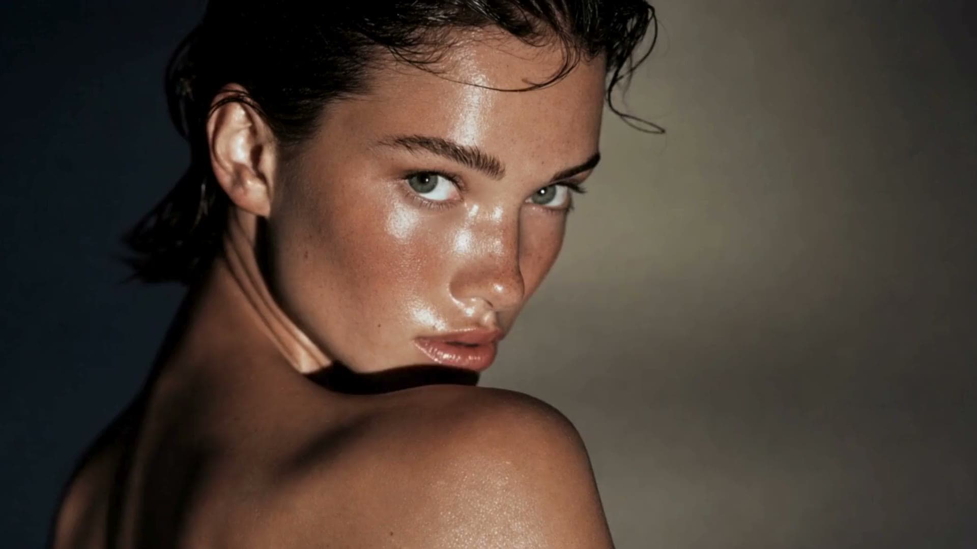 A beauty campaign in motion: a look over the shoulder, wet skin, eyes, a satin slip dress and its shadow on a lit wall