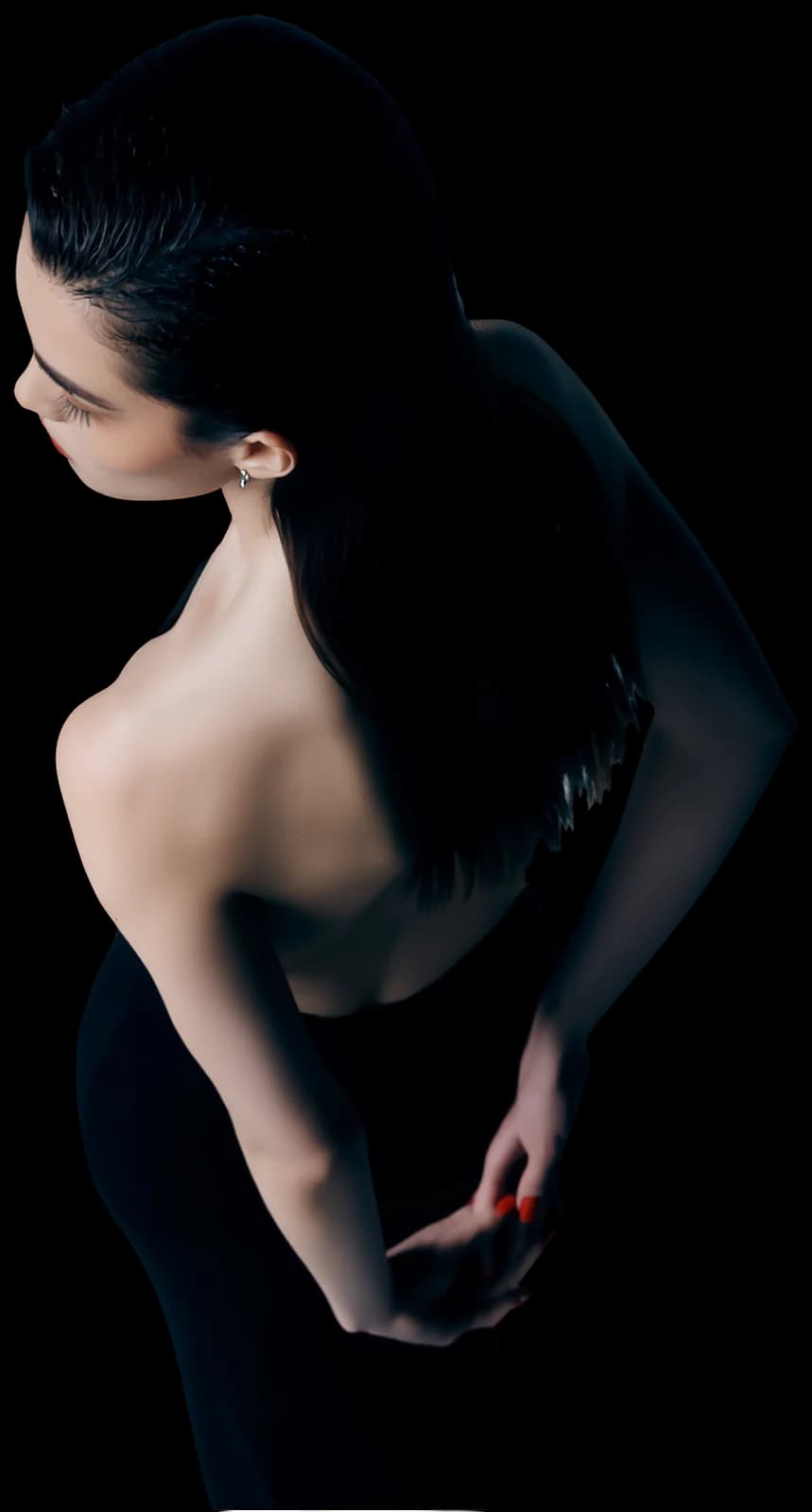 A woman in a black dress seen from above, looking down over her shoulder
