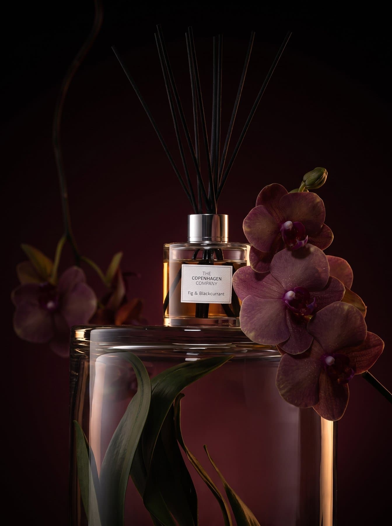 A Signature diffuser beside a dark orchid