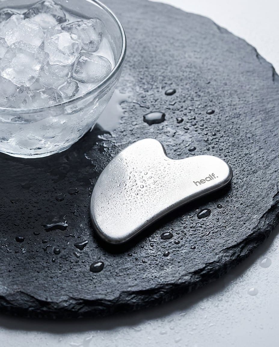 The steel gua sha on slate, beaded with ice water