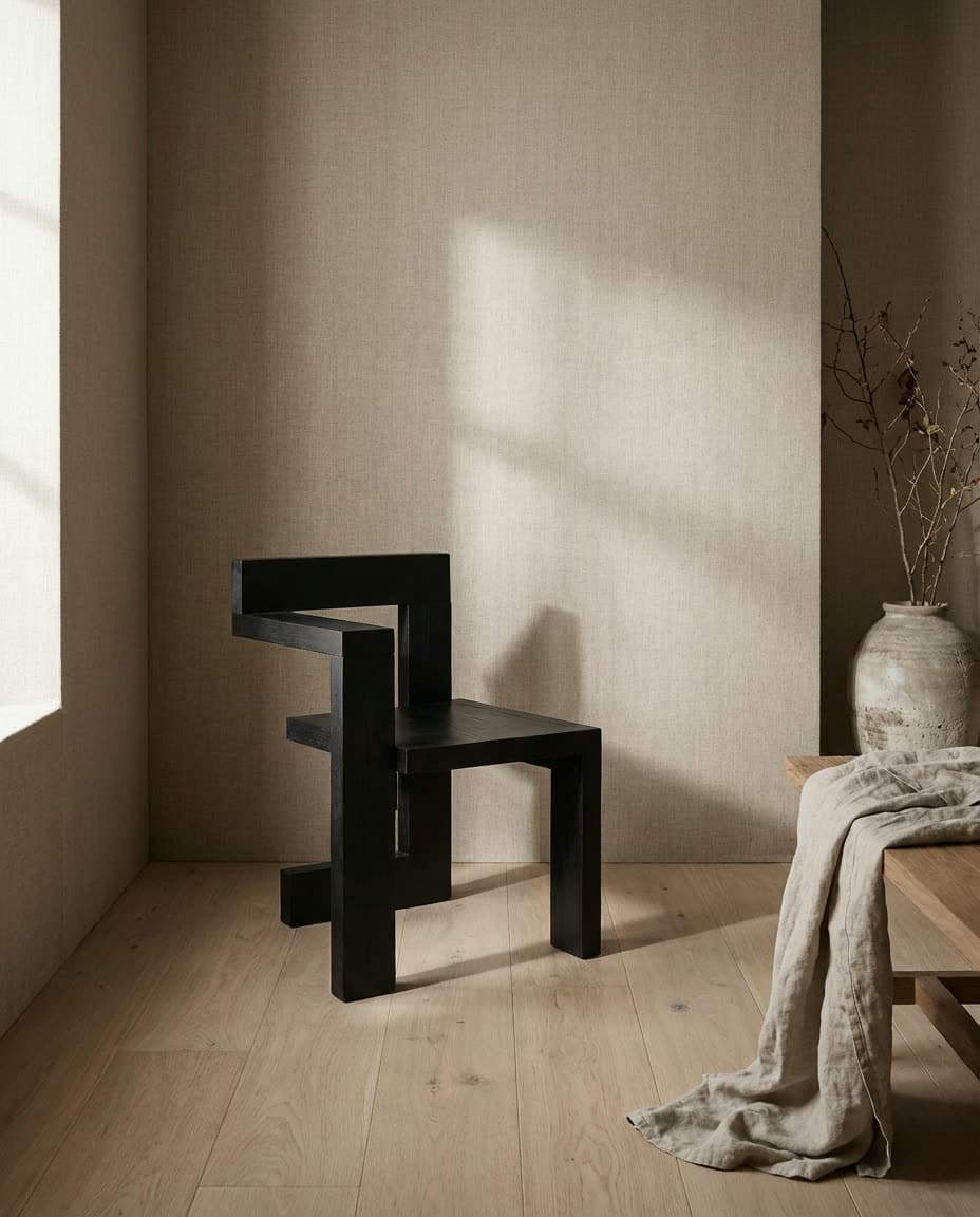 A black chair and a draped cloth in a sunlit plaster room